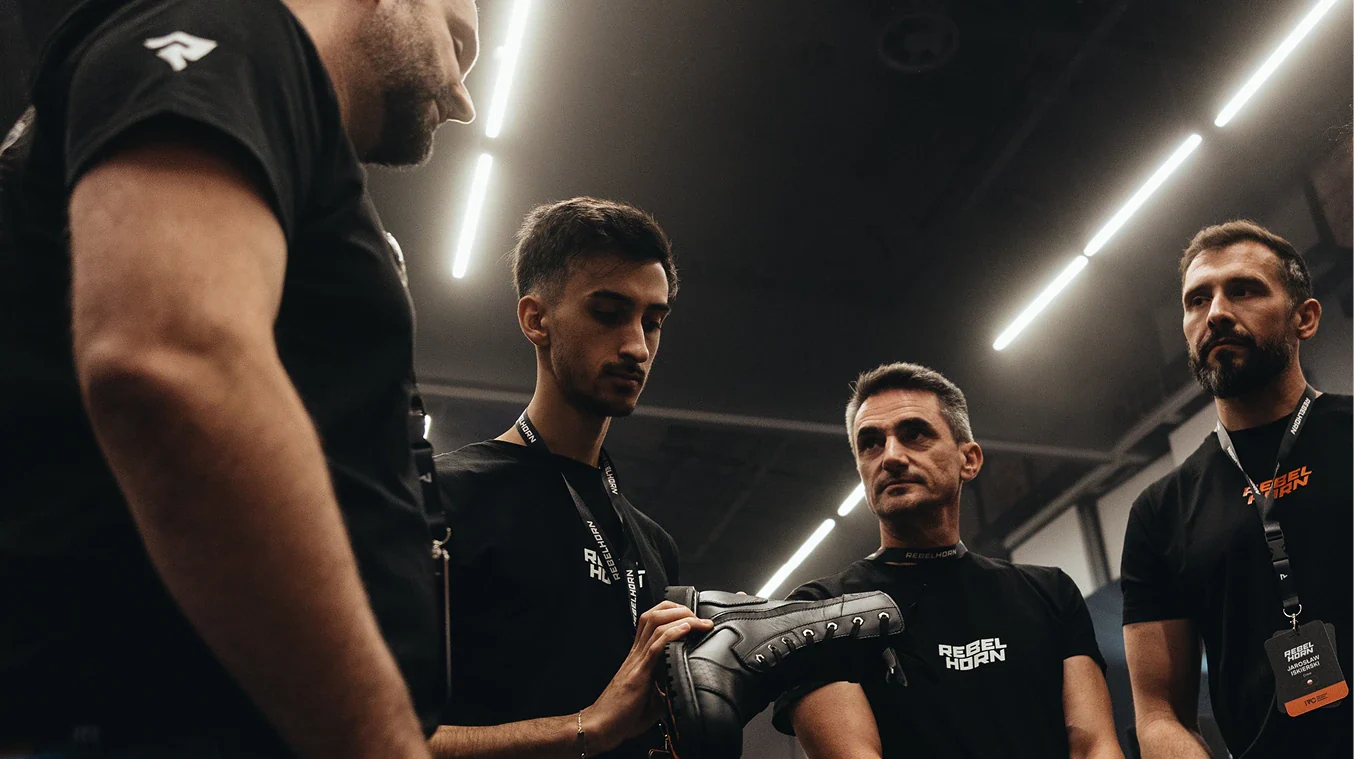 Group of men in a dark indoor setting, one holding a black object.